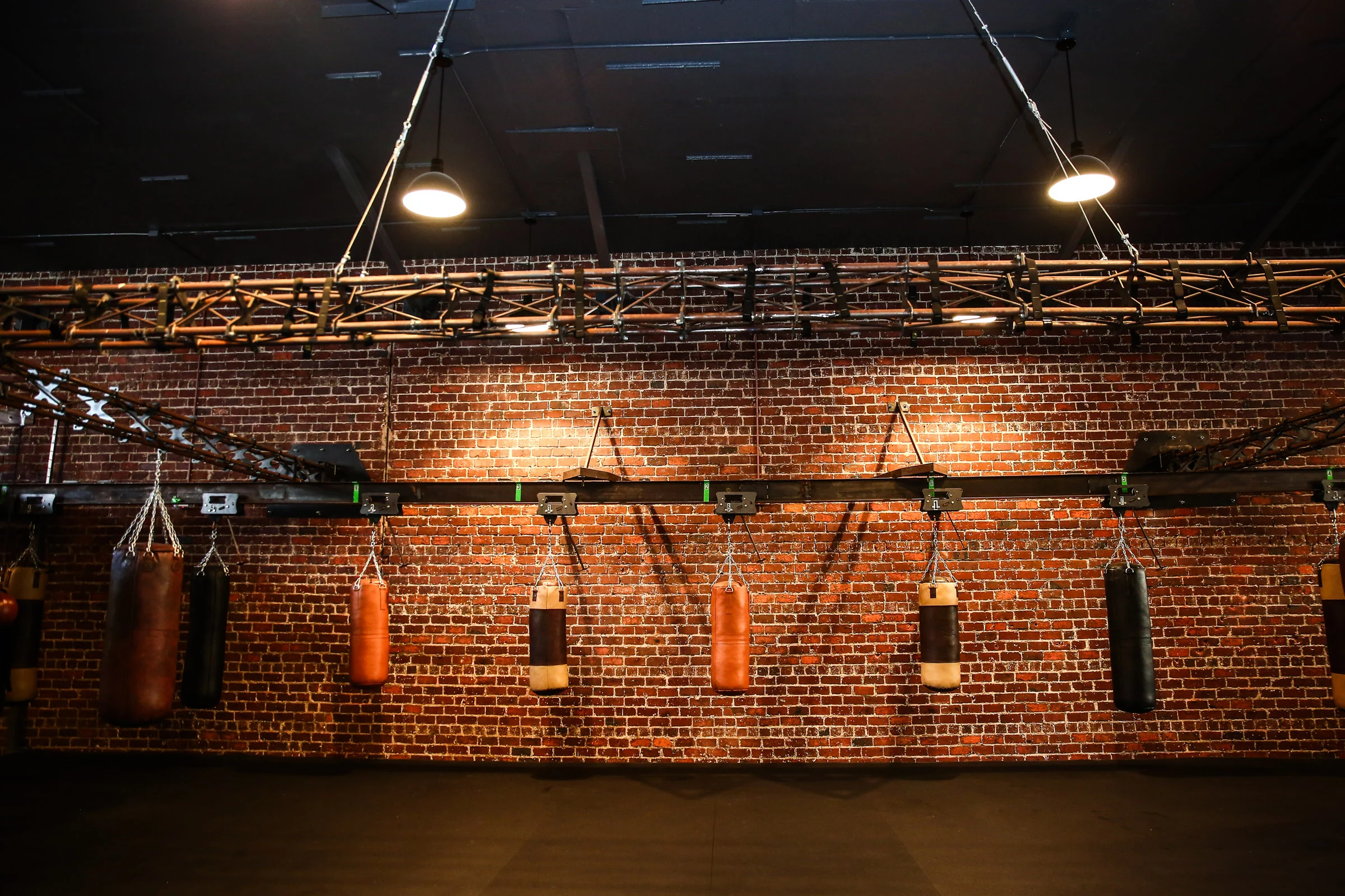 A row of leather heavy bags against the brick wall inside GGG Boxing Club
