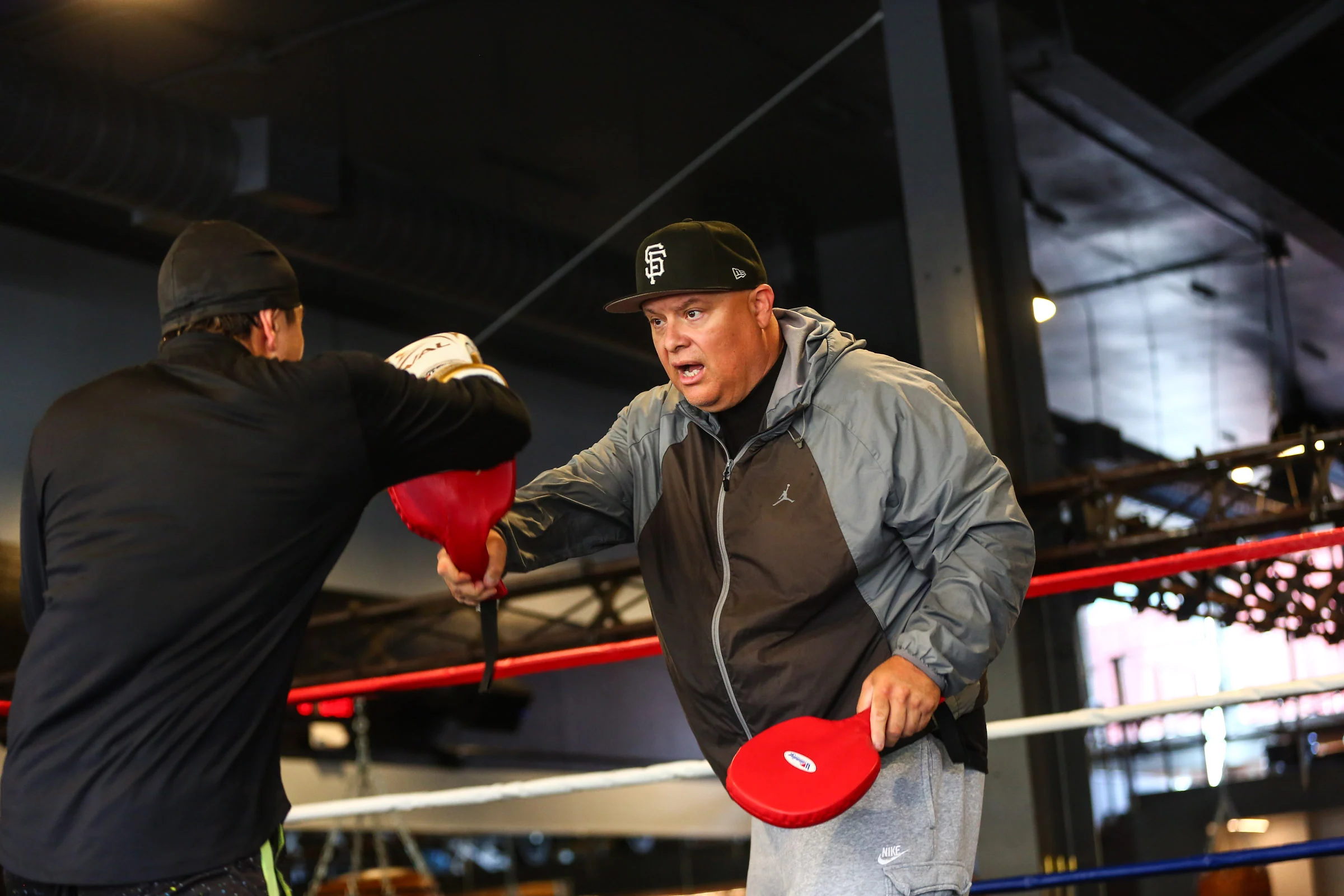 One-on-one boxing instruction with a GGG coach holding red focus mitts