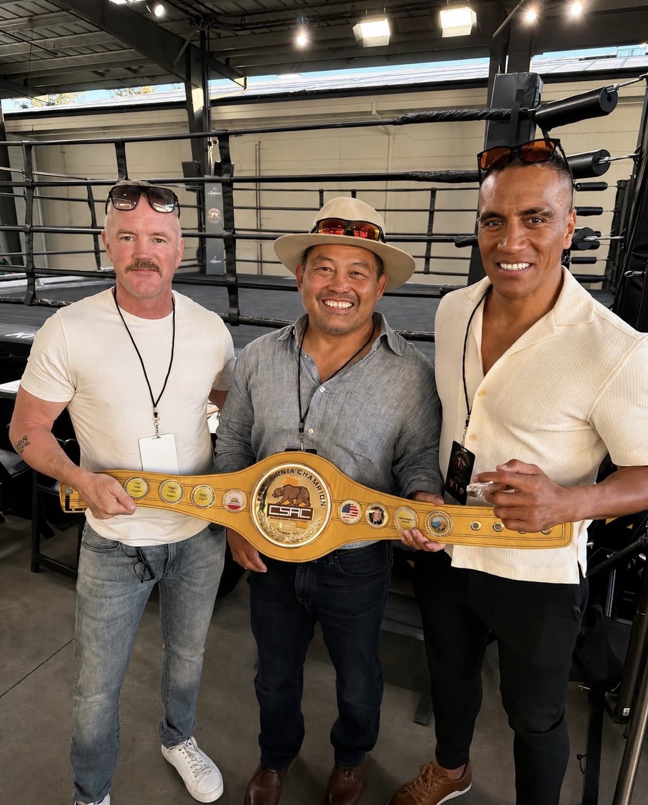 The three GGG founders holding a California championship belt beside a boxing ring